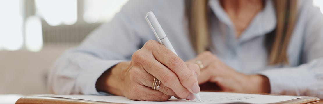 Close-up view of woman writing on a document.